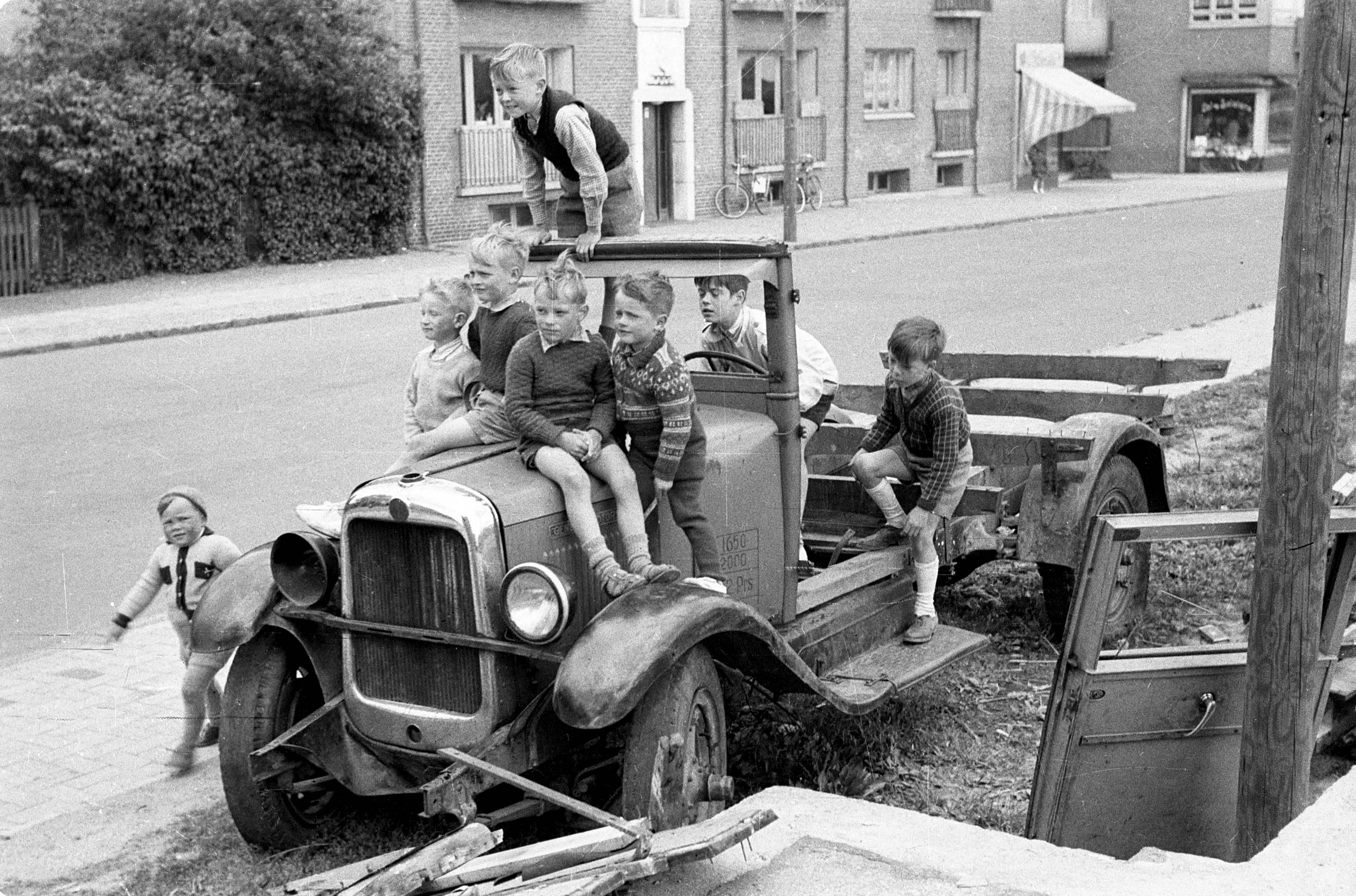 1952. En flok drenge morer sig med en gammel bil.
